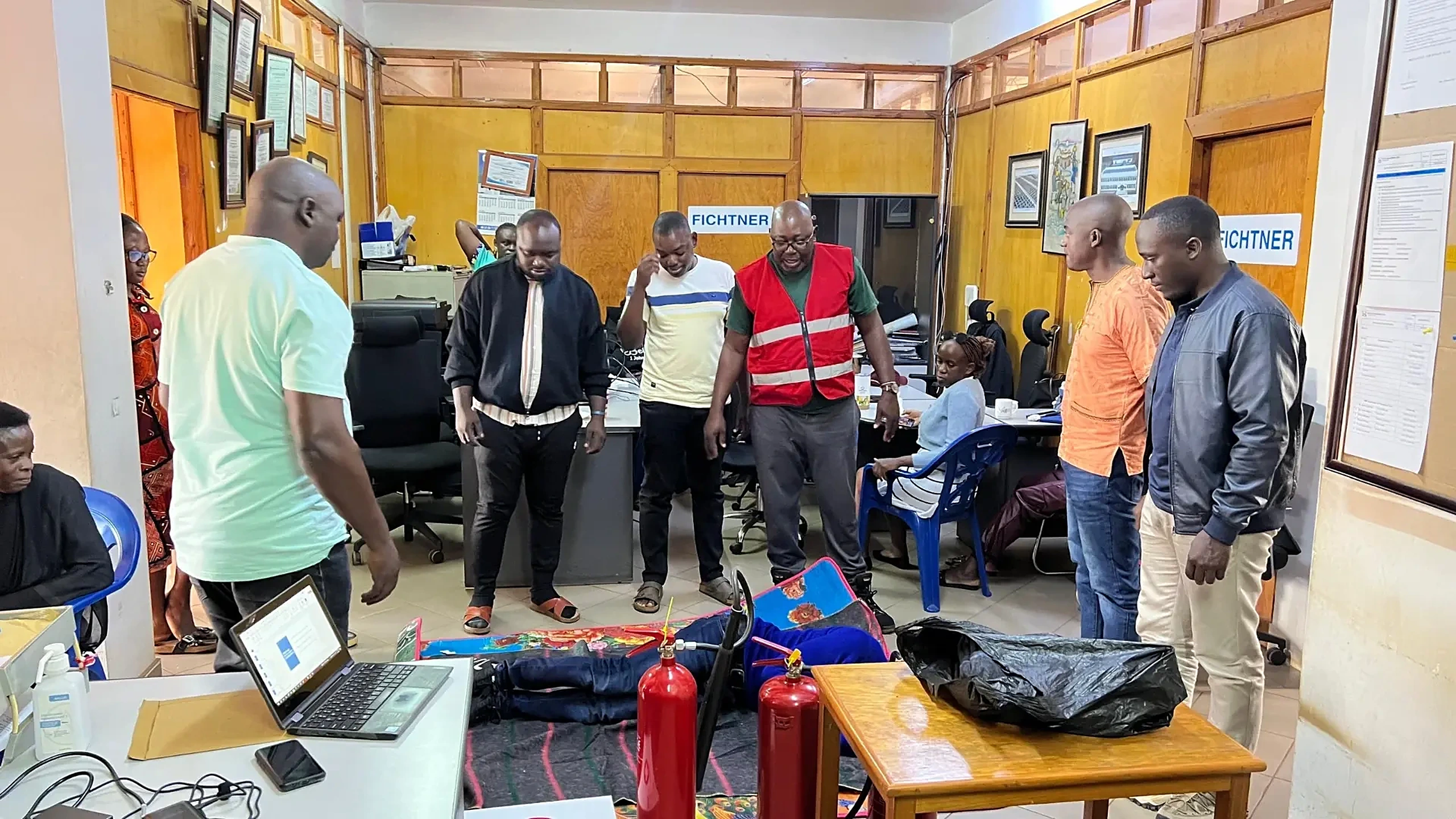Trainer demonstrating casualty handling and first aid on a mat to office staff during an emergency response session