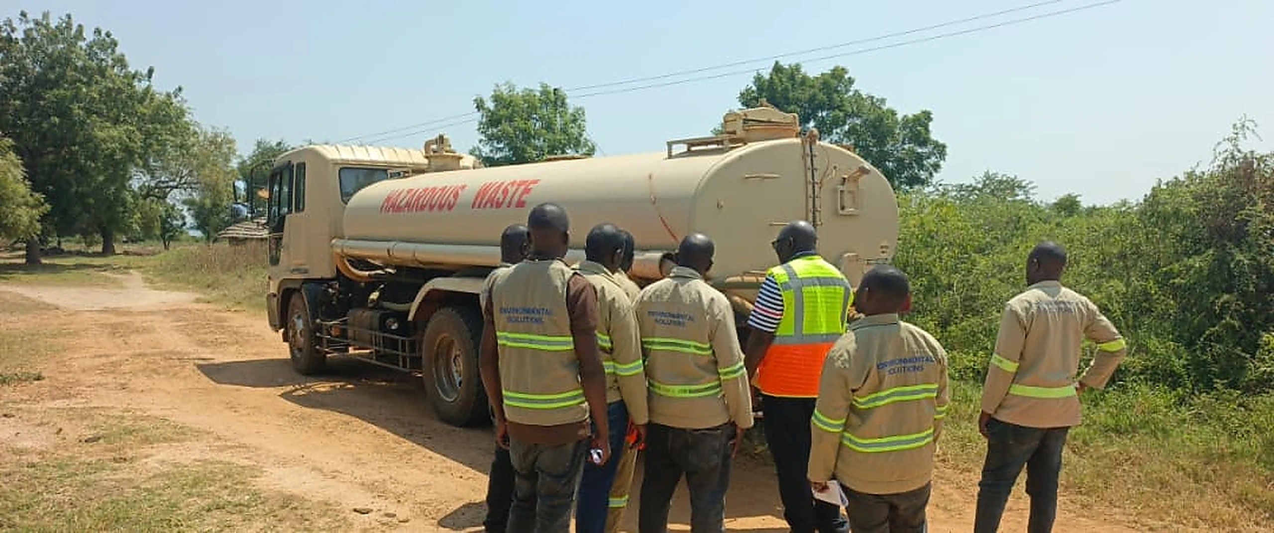 Environmental solutions crew receiving hazardous waste handling training beside a hazardous waste tanker truck